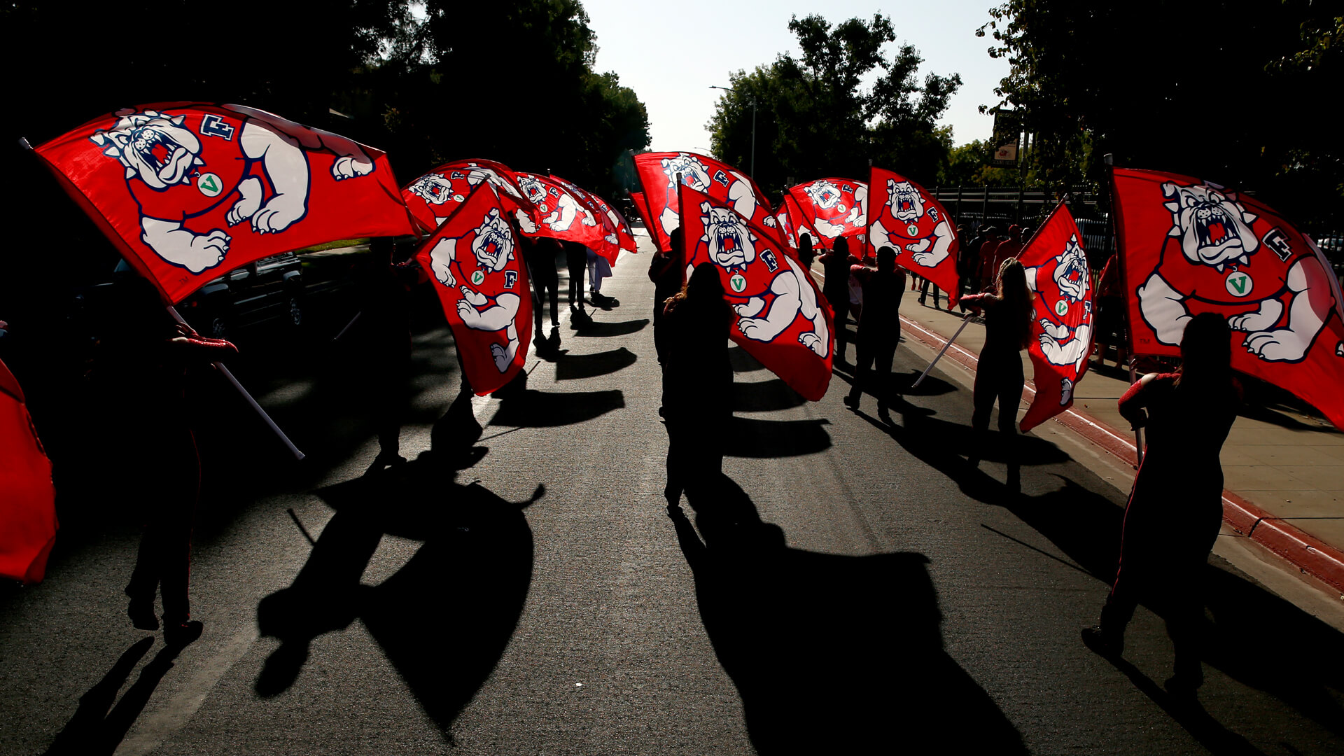 Fresno State students marching with Fresno State flags