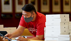 Student holding digital device next to stack of iPads